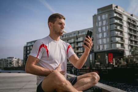 Sportler mit Atemtrainer und Smartphone